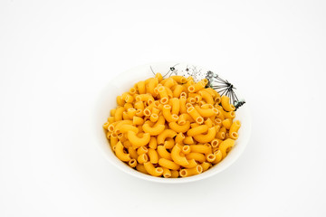 Uncooked macaroni in a bowl isolated on white background with space for text, flat lay concept. 