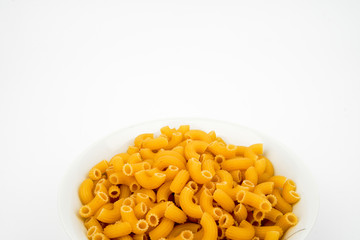 Uncooked macaroni in a bowl isolated on white background with space for text, flat lay concept. 