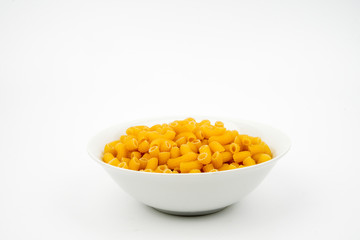 Uncooked macaroni in a bowl isolated on white background with space for text, flat lay concept. 