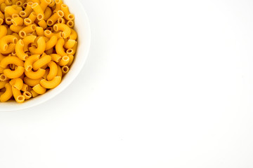 Uncooked macaroni in a bowl isolated on white background with space for text, flat lay concept. 