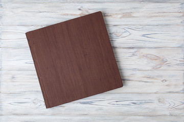Family photo book with embossing. Photo book on a light background. Brown  photo book with  leather cover. Photoalbum with a hard cover on a wooden background. Wedding photo album.