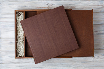 wedding photo book with wooden box. cardboard box for a family photo album. Box for wedding album on the wooden background. Gift box with lid.