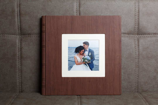 Photo book on grey background close up portrait. Brown  wedding photo album with  leather cover.  Wedding photoalbum with a hard cover . Family photo book with embossing. 