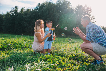 Happy family blowing soap bubbles in summer day.