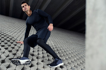 Sports man climbing at concrete grey wall, and doing his training in urban area scenery. Concept of achieve goals.