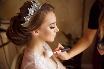 Stylist makes makeup bride on the wedding day. Makeup artist preparing beautiful girl before  wedding, in morning