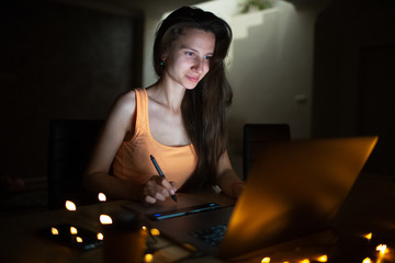 Portrait of young designer girl working at graphic tablet on laptop. Dressed in yellow wearing glasses.