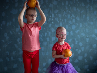 Caucasian children in pink t-shirt and stockings with yellow grapefruit on floor. Boys posing for...