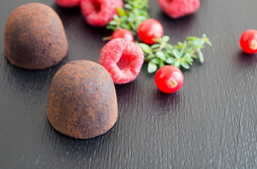 Candy truffles on black background with raspberry.