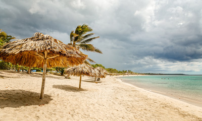 Rancho Luna sandy beach with palms and straw umrellas on the shore, Cienfuegos, Cuba