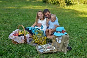 Happy family resting in the Park on the grass at sunset. They play and smile. Family picnic outdoors. Portrait. Horizontal view