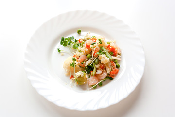 couscous with vegetables, shrimp and radish on a white plate