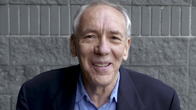 Portrait of senior citizen snickering into camera.