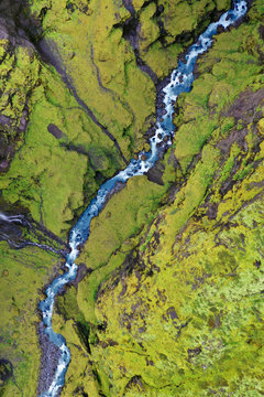 Aerial View Looking Down on Blue Stream Winding Through Green Hilled Ravine