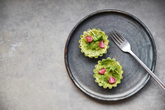 Two tartlets on a dark plate in a restaurant. Gourmet dish.