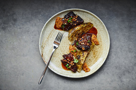 Gourmet pork cheek dish with baked celery root and french mustard