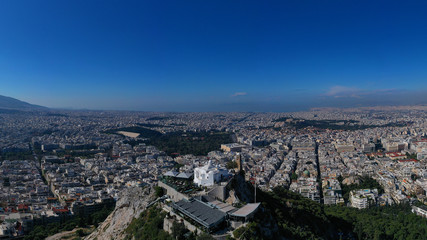 Aerial drone panoramic photo of iconic Saint George Lycabettus chapel as seen from top of hill, all Athens cityscape and Acropolis hill at the background, Athens historic centre, Attica, Greece
