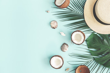 Summer composition. Tropical palm leaves, hat, coconut on pastel blue background. Summer concept. Flat lay, top view, copy space