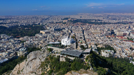 Naklejka premium Aerial drone panoramic photo of iconic Saint George Lycabettus chapel as seen from top of hill, all Athens cityscape and Acropolis hill at the background, Athens historic centre, Attica, Greece