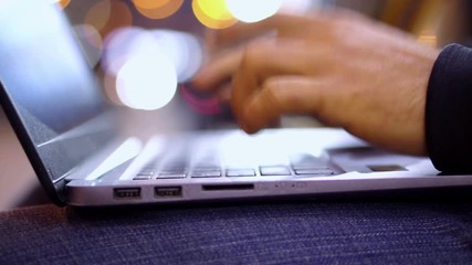Close-up View of Man working at Laptop in the evening city street with bokeh light effect