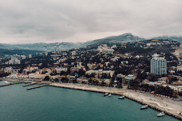 Aerial view of Yalta embankment from air in winter day. City on mountains and coastline with buildings and beautiful nature