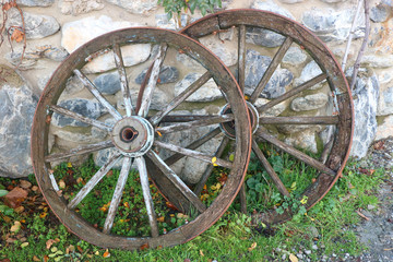 Two old horse wagon wooden wheels placed on a stone wall 