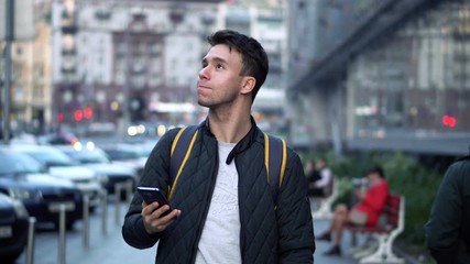 Young Attractive Man Walking on Street and Using Smartphone