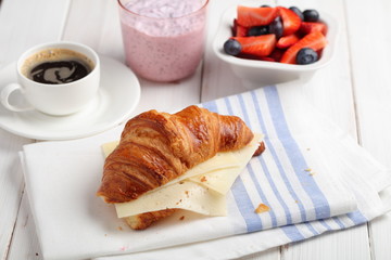 French breakfast: croissant sandwich with cheese, fruit salad, chia seeds yogurt, and coffee