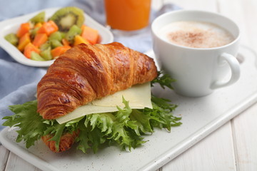 French breakfast: croissant sandwich with cheese, fruit salad, and coffee