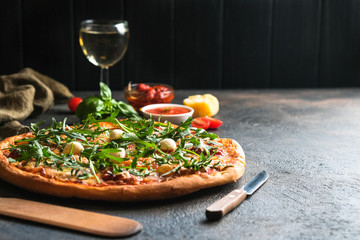Traditional Italian pizza with wine on a dark background copy space.