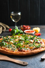 Traditional Italian pizza with wine on a dark background.
