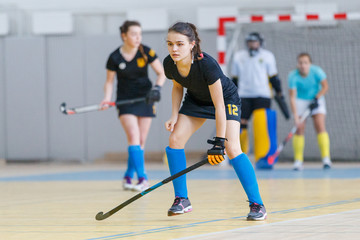 Young female indoor hockey player with stick