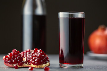 Pomegranate juice in a glass on gray background.