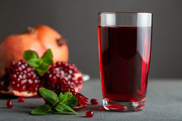 Pomegranate juice in a glass on gray background.