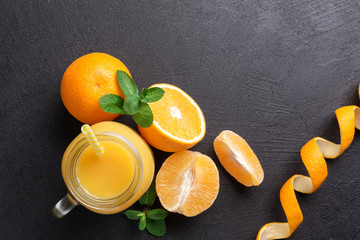 A group of oranges and a jar of juice on a dark background.