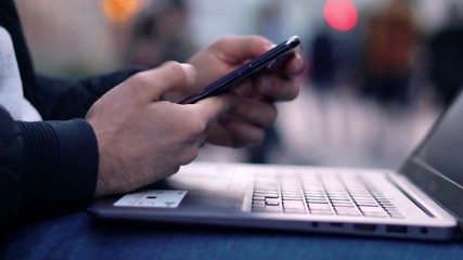 Close-up View of Man working at Laptop in the evening city street with bokeh light effect