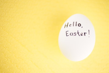 White chicken egg with black inscription hello easter
