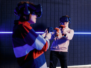 young guy and girl in a virtual reality helmet playing video games in a club