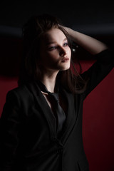 Fototapeta na wymiar Young beautiful female fashion model in a business stylish suit on a red and black background.