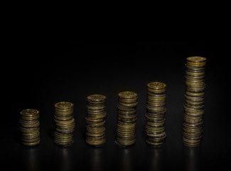 Gold coin stack isolated on dark background. Stacks of gold coins of various heights. Vertical bar chart.