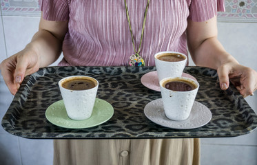 Fototapeta na wymiar Woman serving Turkish coffee on a tray. Traditional Turkish drink as known in native language 