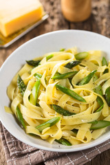 Fresh homemade pasta dish of fettuccine or tagliatelle, green asparagus, garlic and lemon juice in bowl, ground black pepper on top (Selective Focus, Focus one third into the dish)