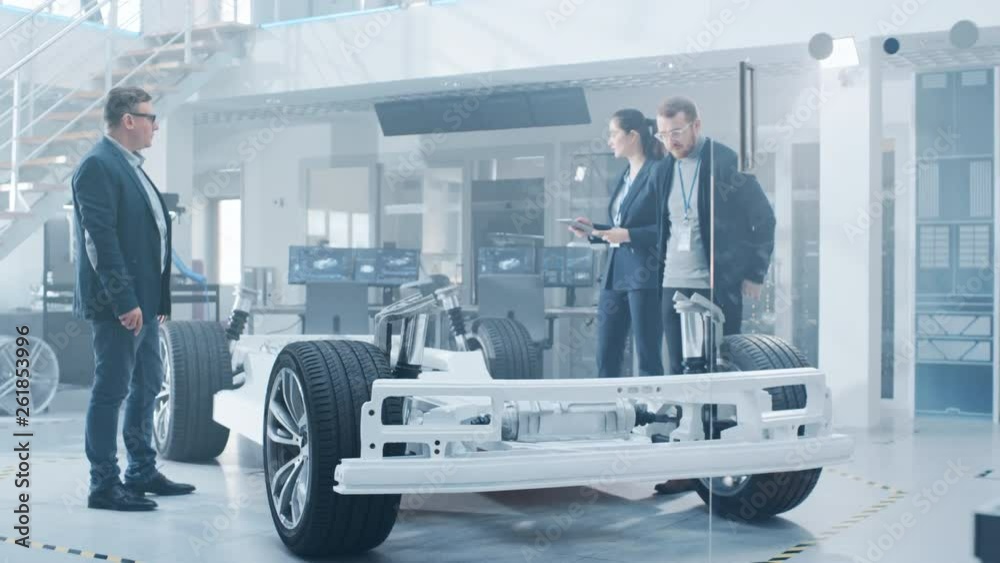 Poster automotive design engineers talking while working on electric car chassis prototype. in innovation l