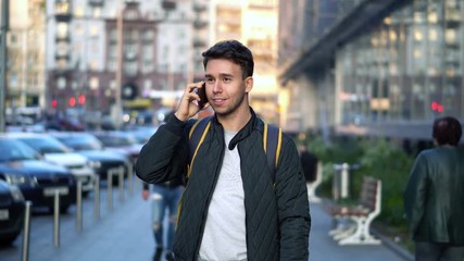 Young Attractive Man Speaking by Phone in the evening city street with bokeh light effect