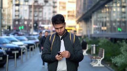 Young Attractive Man Speaking by Phone in the evening city street with bokeh light effect