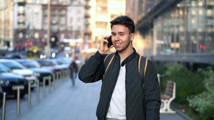 Young Attractive Man Speaking by Phone in the evening city street with bokeh light effect