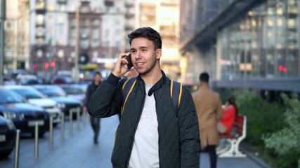 Young Attractive Man Speaking by Phone in the evening city street with bokeh light effect