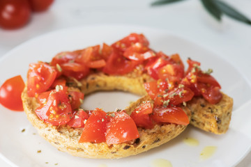 Tipical summer dish of Puglia - friselle. Classical frisella with tomato, oregano and olive oil. Dried bread called freselle. Healthy vegetarian food.