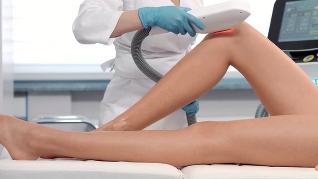 Medium shot of Laser hair removal procedure on female legs.