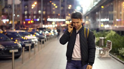 Young Attractive Man Speaking by Phone in the evening city street with bokeh light effect